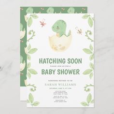 a green and white baby shower card with a dinosaur in an egg