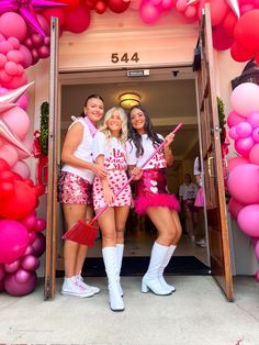 three women dressed in pink and white posing for the camera with balloons behind them at a party