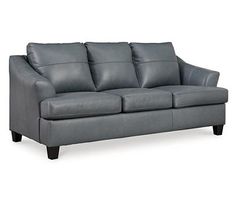 a gray leather couch with four pillows on it's arms and backrests