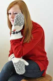 a woman sitting on top of a wooden bench wearing mittens and holding her hand up to her face