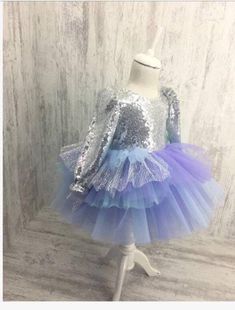 This dress has a silver sequin top and bow and a mermaid colored tutu skirt. Party Sequin Tulle Dress With Contrast Sequin, Party Sequin Dress With Contrast Sequin On Tulle, Party Sequin Dress With Contrast Sequins And Tulle, Silver Tulle Party Dress, Holiday Princess Tutu Dress With Sequins, Holiday Princess Sequined Tutu Dress, Festive Princess Tutu Dress With Sequins, Long Sleeve Princess Dress With Sequins For Party, Princess Sequin Tutu Dress For Party Season