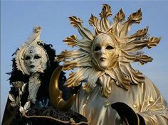 two masks are sitting next to each other in front of a blue sky with white clouds