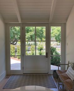 an empty entryway with two benches and large glass doors that lead into the yard