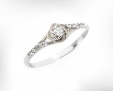 a white gold ring with diamonds on the sides and a knot at the top, set in 18k white gold