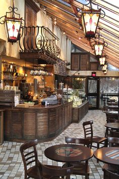 the inside of a restaurant with many tables and chairs, lights hanging from the ceiling