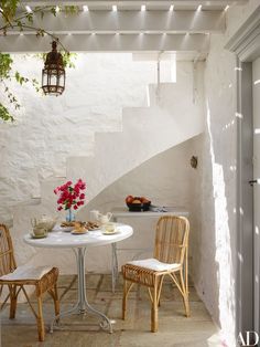 a white table with two chairs and a potted plant on top of it next to a staircase