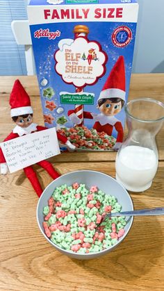 an elf's cereal box and some candy in a bowl next to a glass of milk