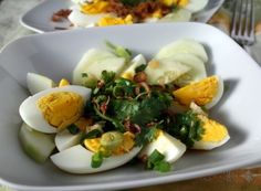 a white plate topped with hard boiled eggs and greens