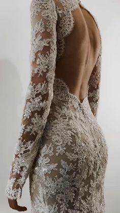 the back of a woman's wedding dress with long sleeves and lace on it