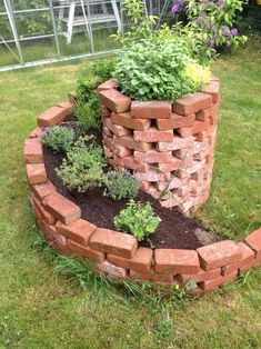 a brick planter with plants growing out of it in the middle of some grass