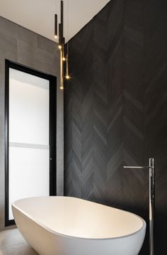 a large white bath tub sitting in a bathroom next to a tall wall mounted light