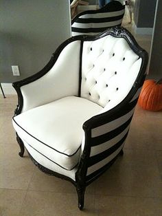 a black and white striped chair sitting on top of a floor next to a pumpkin