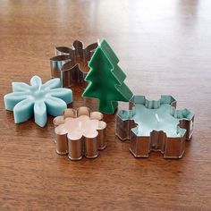 four cookie cutters sitting on top of a wooden table next to a christmas tree