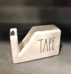 a white tape dispenser with the word tape on it's side