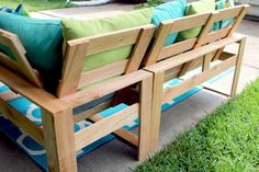 a wooden bench sitting on top of a grass covered field next to a blue and green pillow