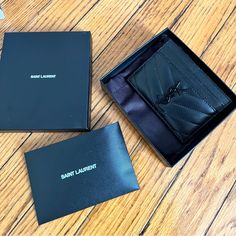 two black leather wallets sitting on top of a wooden table next to each other