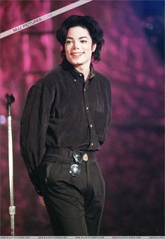 a woman standing in front of a microphone and wearing a black shirt with long sleeves