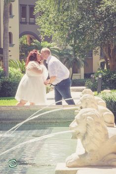 a man and woman standing in front of a fountain