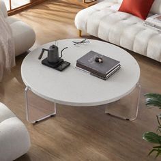 a living room with white couches and a coffee table in the middle on wooden flooring