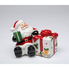 a santa clause figurine sitting next to a gift box on a white background