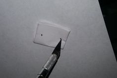 a close up of a pen on top of a piece of paper with a hole in it