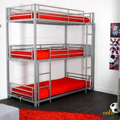 a metal bunk bed with red mattresses in a white room next to a soccer ball