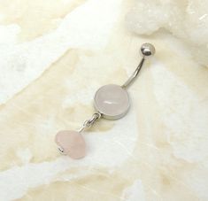 Rose Quartz Belly Ring Show off your beautiful belly! Rose quartz dangle style belly ring features a gorgeous soft pink rose quartz gemstone cabochon with a hand wire wrapped rose quartz nugget that dangles below. You choose 8mm setting or 10mm setting. The rose quartz stone is a universal favorite and is translucent pink with lineal opaque pink patterns. Rose quartz is a natural stone and does vary in color slightly, sometimes it is more translucent and in the surgical steel settings can appear Pink Belly Rings For Wedding, Wire Wrapped Rose, Dangle Belly Rings, Belly Button Piercing, Body Piercings, Rose Quartz Stone, Ring Simple, Navel Rings, Tanning Lotion