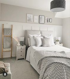 a bedroom with white and gray bedding, pictures on the wall above the bed