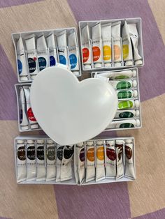 an assortment of paint tubes with a heart shaped container