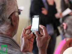 an older man is looking at his cellphone while others are standing in the background