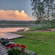 a boat is sitting on the shore of a lake near a dock and some flowers