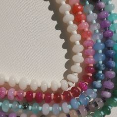 several different colored beads are arranged in a circle on a white surface, with one bead at the end