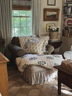 a living room filled with furniture and bookshelves next to a window covered in curtains