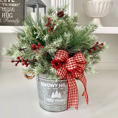 a christmas plant in a metal bucket with red and white bows on the top, sitting on a table