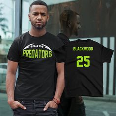 a man standing in front of a window with a black shirt that says predators on it