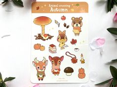 an animal crossing autumn sticker sheet on a white surface with flowers and leaves around it