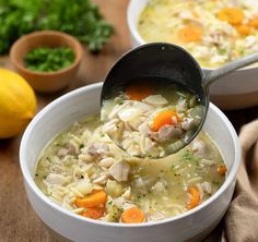 a bowl of chicken noodle soup with a ladle full of the soup is ready to be eaten