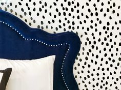 a bed with black and white polka dots on the wall next to it's headboard