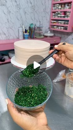 someone is decorating a cake with green icing and sprinkles on it