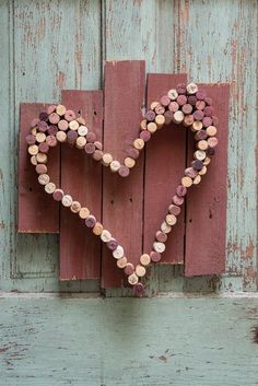 a heart made out of wine corks hanging on a wooden wall next to a door