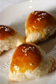 three rolls with sesame seeds are on a white plate