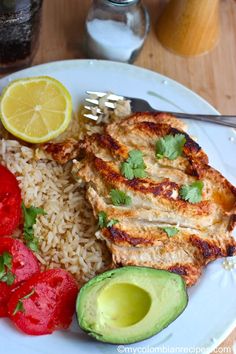 the meal is prepared and ready to be eaten with avocado, rice, tomatoes, and chicken