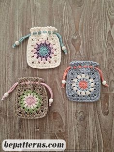 three crocheted bags sitting on top of a wooden table