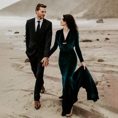 a man and woman walking on the beach holding hands