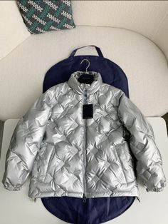 Indulge in the luxurious warmth and iconic style of our Glossy Puffer Jacket, capturing the essence of Louis Vuitton Design. Its lustrous diamond-quilted design and flattering silhouette will keep you cozy and effortlessly chic all season. This is a high quality replica. Luxury Puffer Jacket With Padded Collar, Luxury Quilted Puffer Jacket, Elegant Long Sleeve Puffer Jacket, Luxury Puffer Outerwear, Luxury Silver Outerwear For Winter, Luxury Long-sleeve Quilted Outerwear, Luxury Quilted Long Sleeve Outerwear, Luxury Winter Puffer Jacket, Luxury Puffer Jacket For Cold Weather