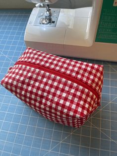 a red and white checkered bag next to a sewing machine