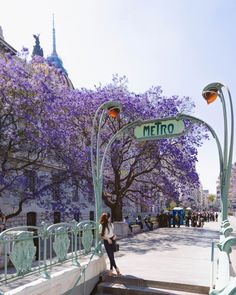 a woman is standing on the steps in front of a street sign that says metro