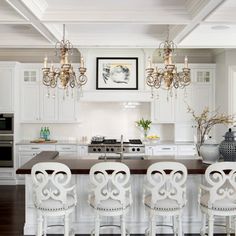 a kitchen with white cabinets and chandeliers