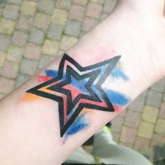 a colorful star tattoo on the wrist