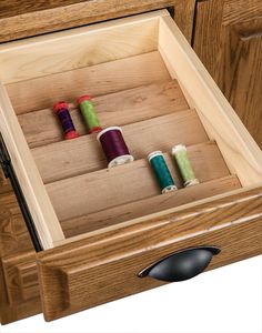 an open drawer with spools of thread in it